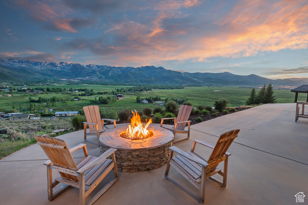 Patio terrace at dusk featuring an outdoor fire pit, a mountain view, and a patio