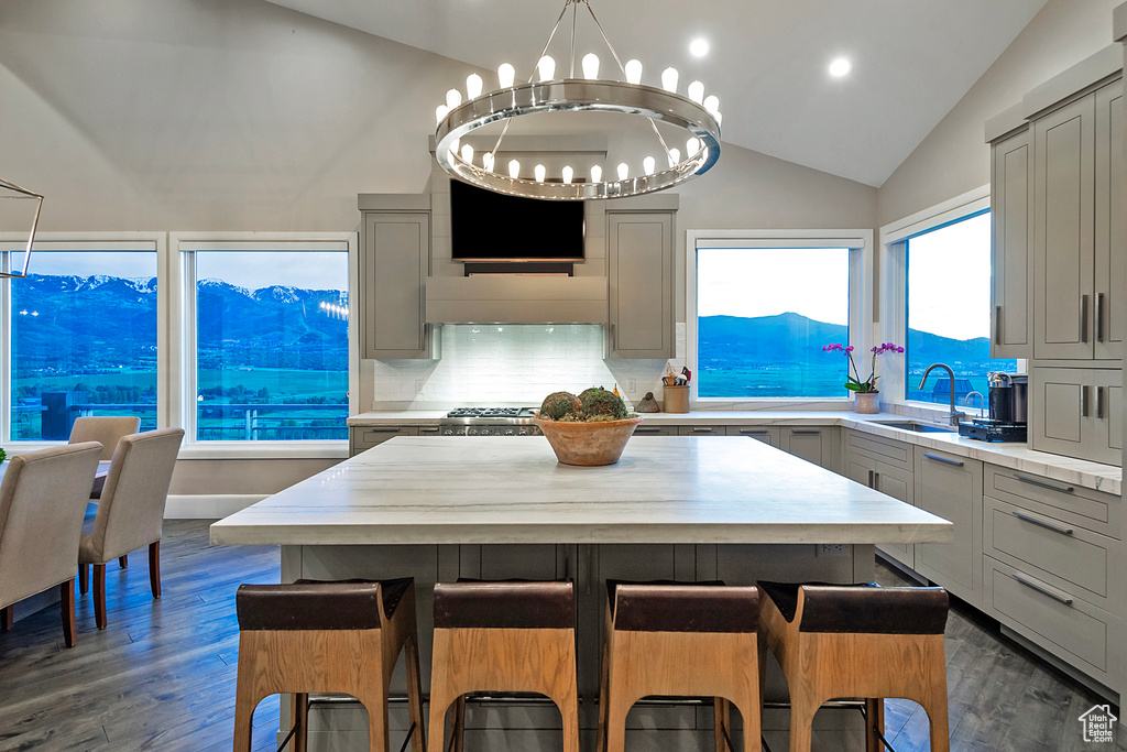 Kitchen featuring gray cabinetry, lofted ceiling, light countertops, a sink, and a breakfast bar area