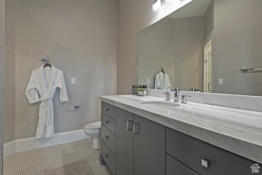 Bathroom with toilet, vanity, tile patterned flooring, and baseboards