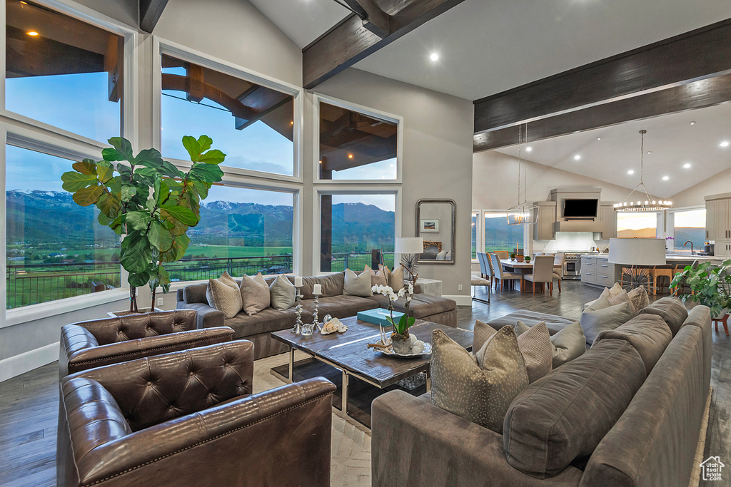 Living area with high vaulted ceiling, beamed ceiling, baseboards, wood finished floors, and a mountain view