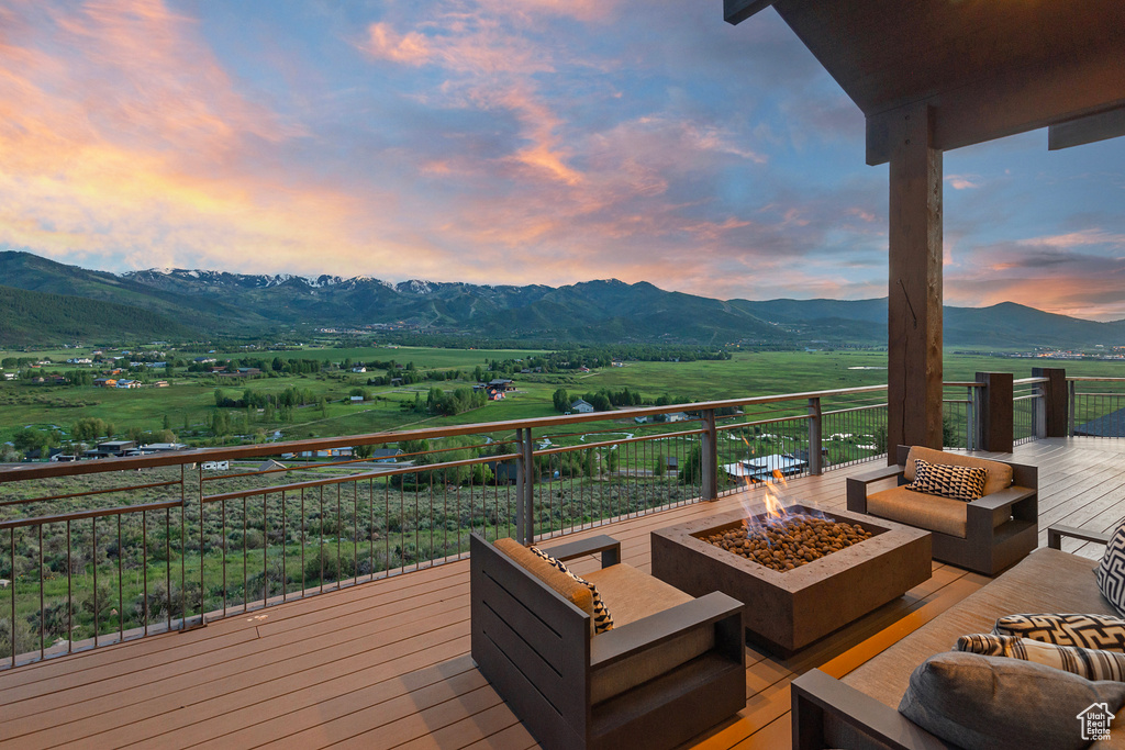 Deck featuring an outdoor living space with a fire pit, a mountain view, and a view of countryside
