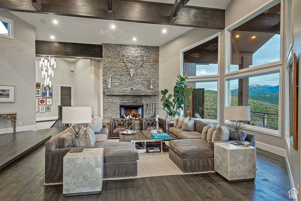 Living area featuring baseboards, a high ceiling, dark wood finished floors, beamed ceiling, and recessed lighting