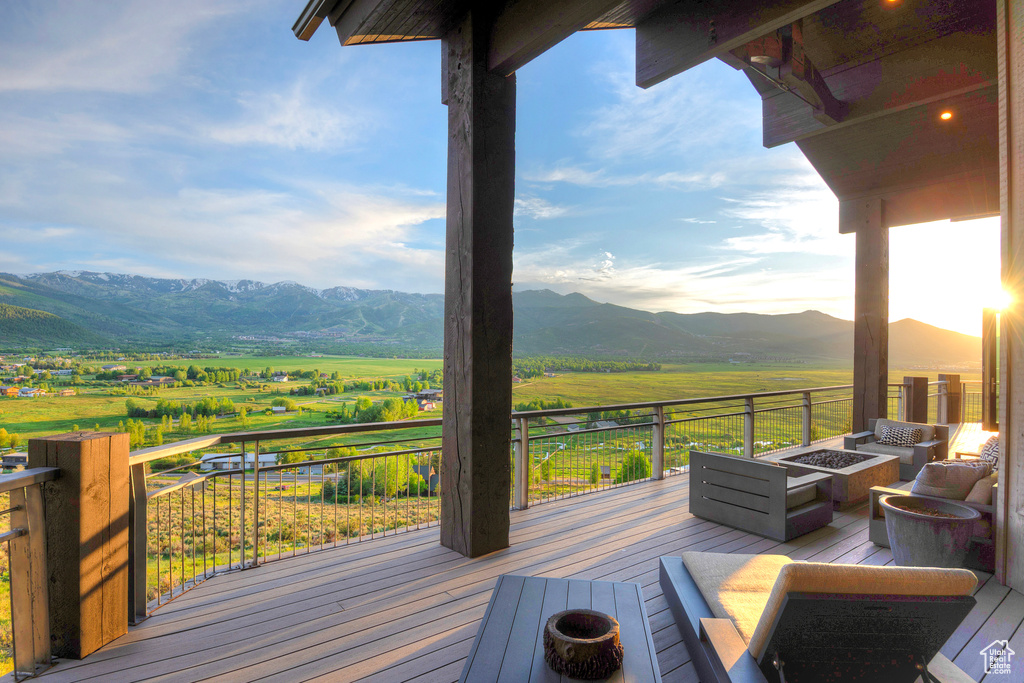 Wooden deck with a fire pit, a mountain view, and a view of countryside