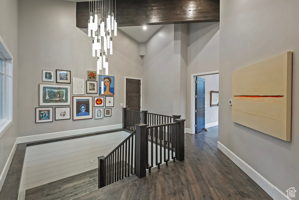 Corridor featuring an upstairs landing, a towering ceiling, baseboards, and wood finished floors