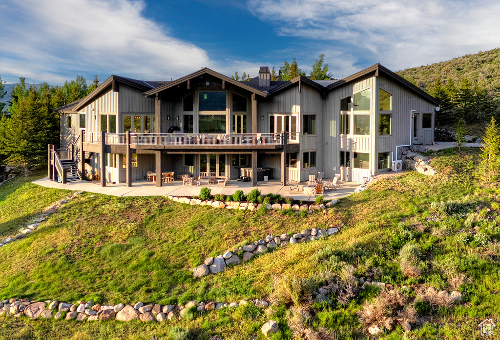 Rear view of house featuring a patio area, a chimney, and a wooden deck