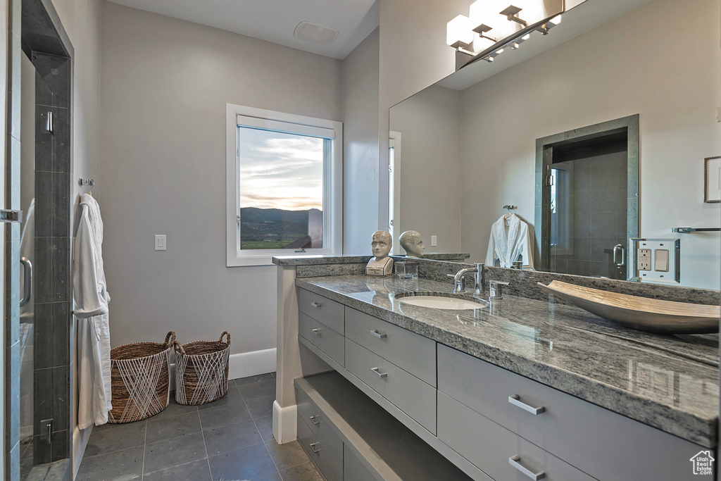 Bathroom featuring vanity, tile patterned flooring, a stall shower, and baseboards