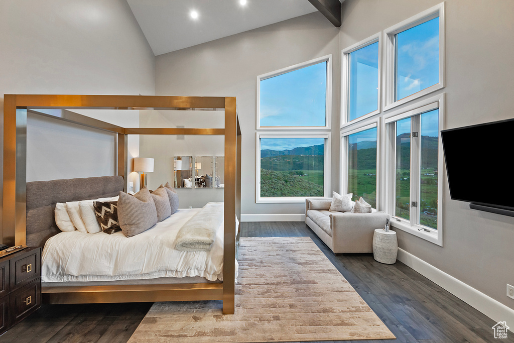 Bedroom with high vaulted ceiling, dark wood-style floors, and baseboards