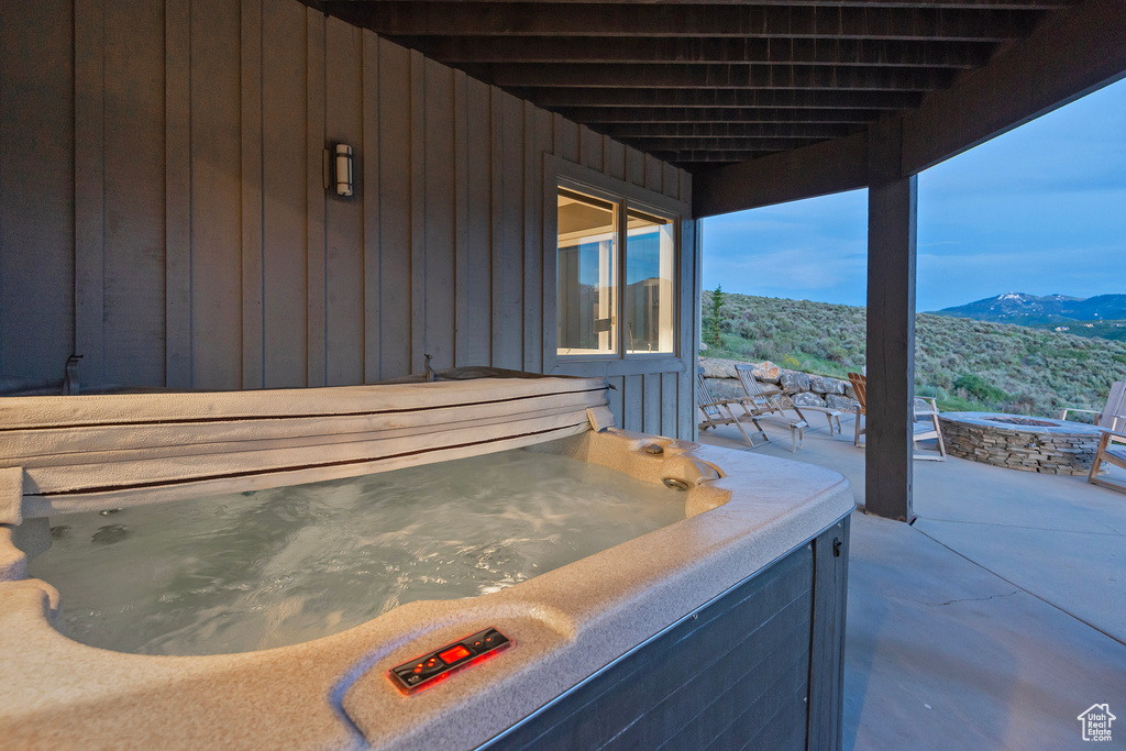 View of patio featuring an outdoor fire pit, a mountain view, and a hot tub