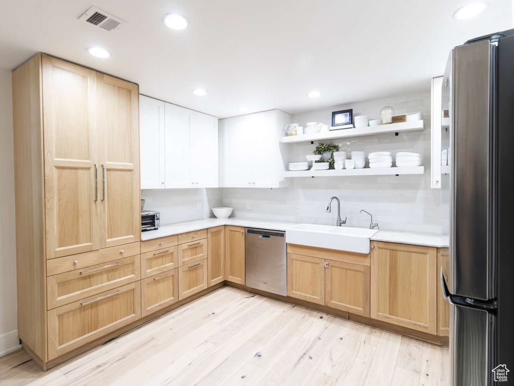 Kitchen featuring stainless steel appliances, light brown cabinets, a sink, light countertops, and recessed lighting