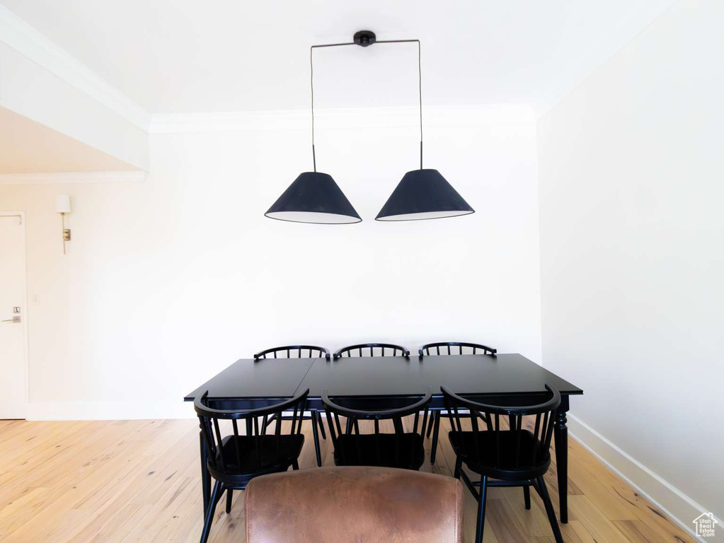 Dining room with crown molding, light wood-style floors, and baseboards