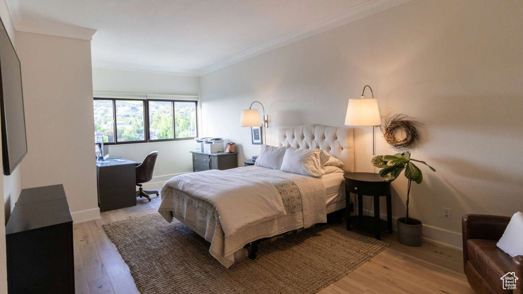 Bedroom featuring light wood finished floors, crown molding, baseboards, and a desk