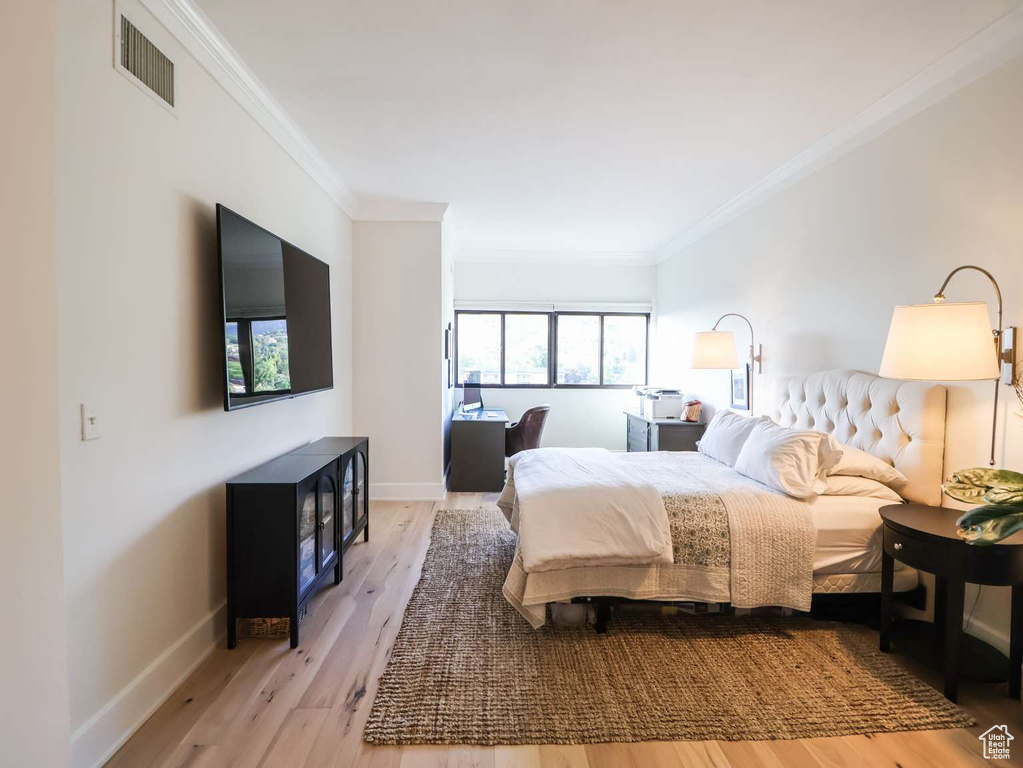 Bedroom featuring ornamental molding, wood finished floors, and baseboards