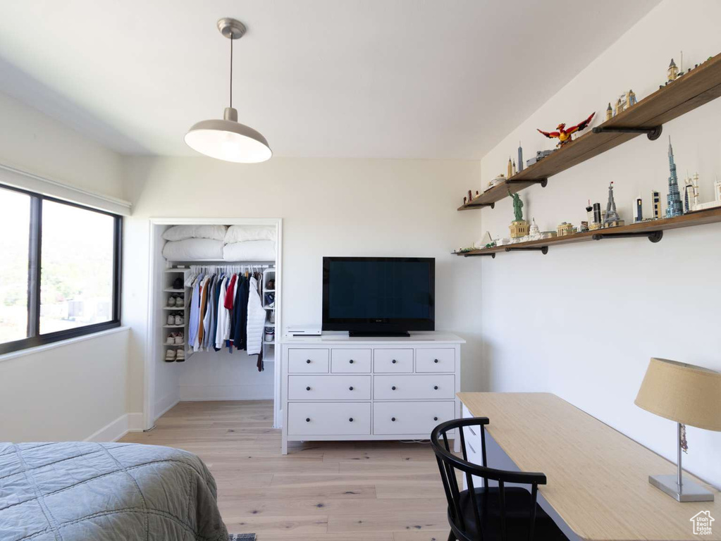 Bedroom with light wood-style floors, a closet, baseboards, an office area, and a spacious closet