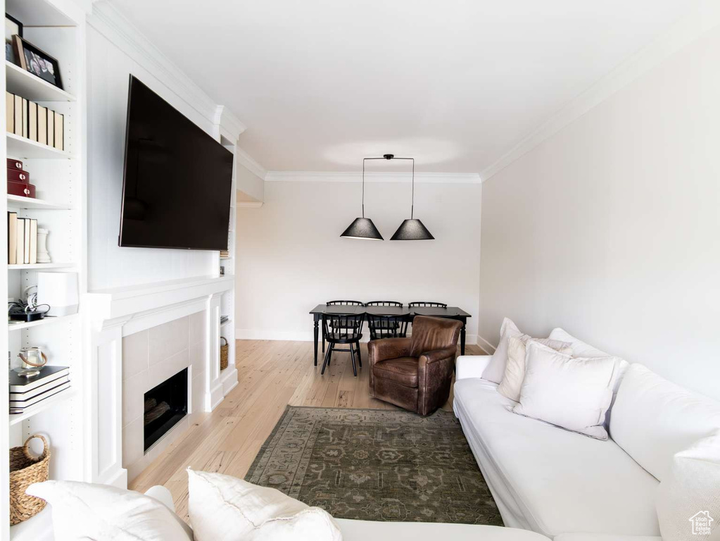 Living area featuring wood finished floors, ornamental molding, a tile fireplace, and baseboards