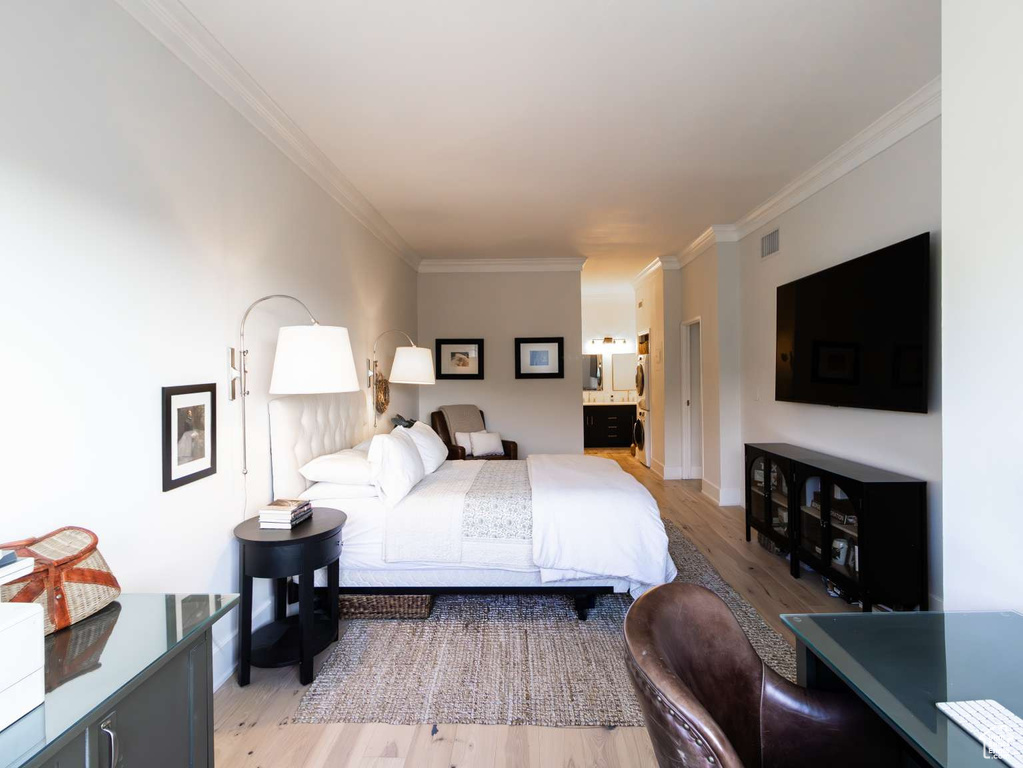 Bedroom featuring light wood finished floors, ornamental molding, ensuite bath, and baseboards