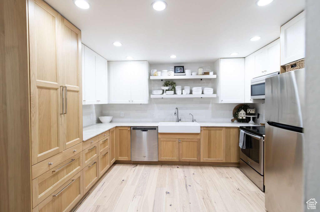 Kitchen featuring appliances with stainless steel finishes, a sink, light countertops, light wood-style floors, and recessed lighting