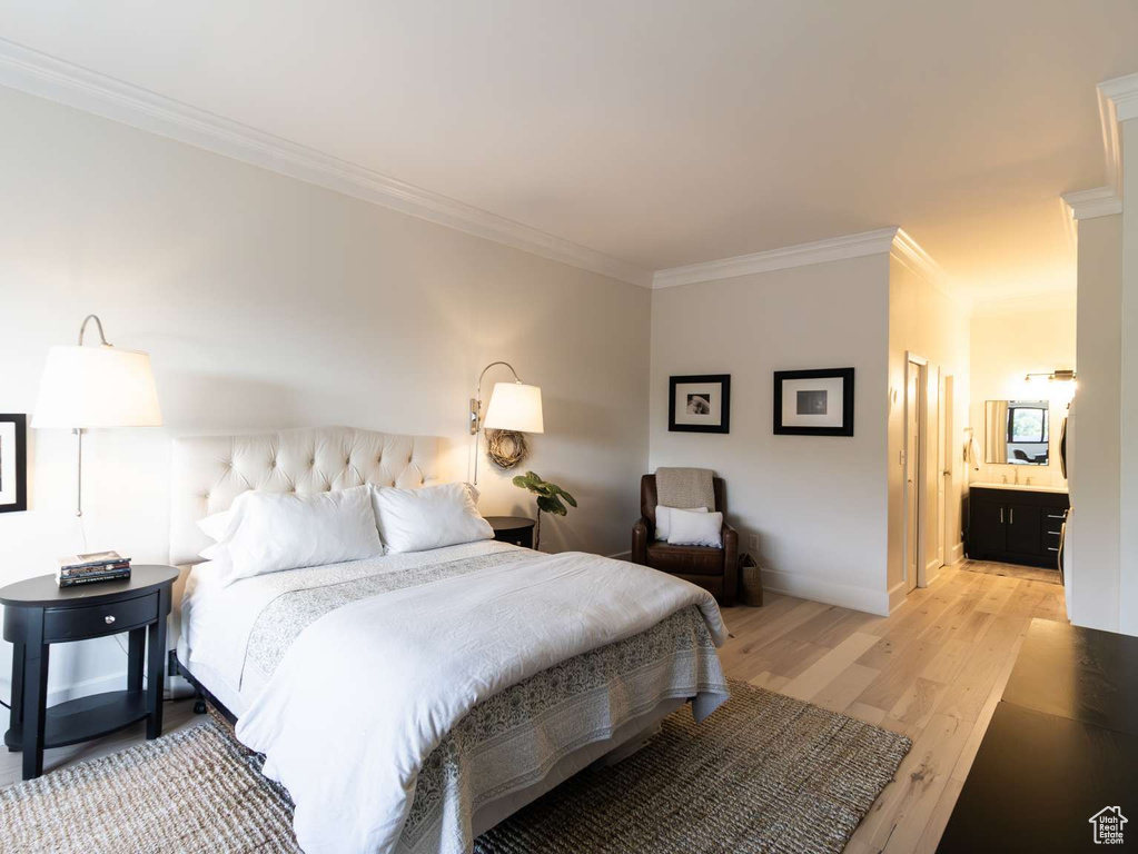 Bedroom featuring crown molding, light wood-style floors, baseboards, and ensuite bathroom