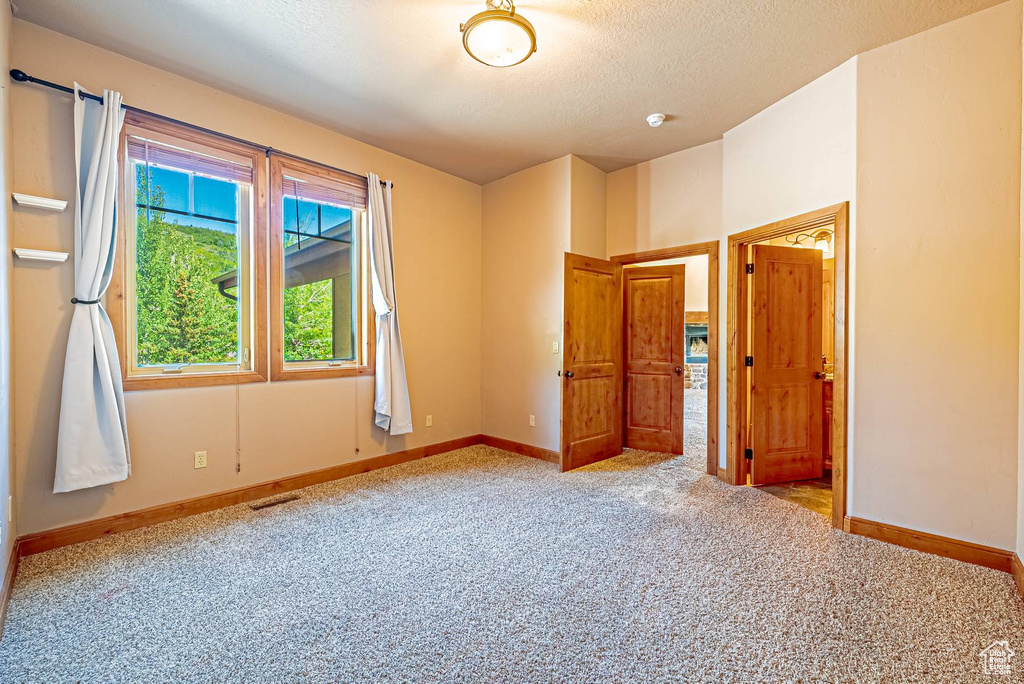 Unfurnished bedroom featuring carpet flooring, baseboards, and a textured ceiling