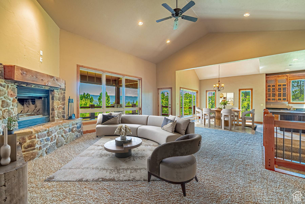 Living area featuring a stone fireplace, high vaulted ceiling, a chandelier, a ceiling fan, and recessed lighting