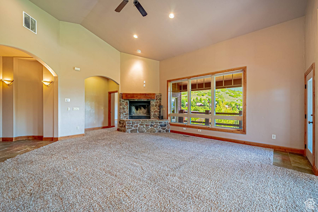 Unfurnished living room with a ceiling fan, carpet, a fireplace, high vaulted ceiling, and baseboards