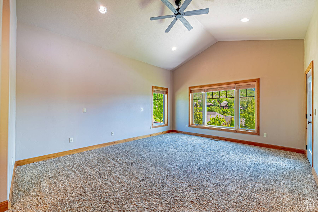 Carpeted spare room featuring baseboards, ceiling fan, vaulted ceiling, healthy amount of natural light, and recessed lighting