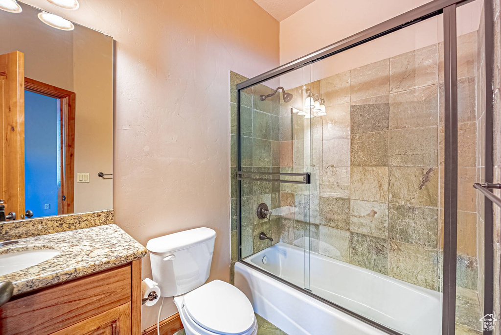 Bathroom with vanity, toilet, and bath / shower combo with glass door