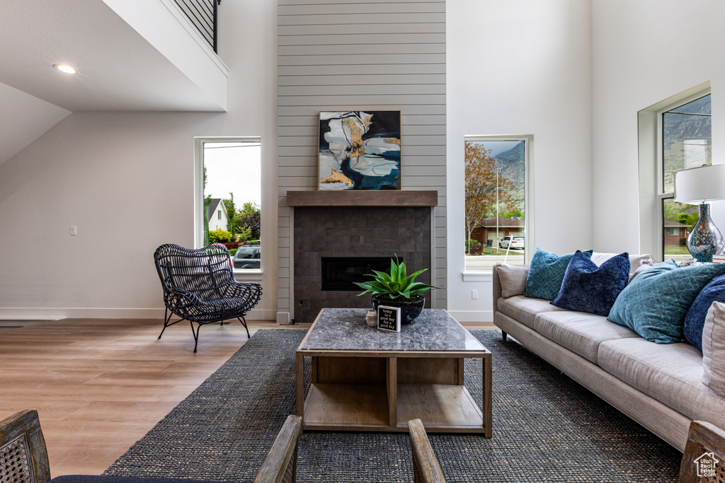 Living area with baseboards, high vaulted ceiling, a large fireplace, and wood finished floors