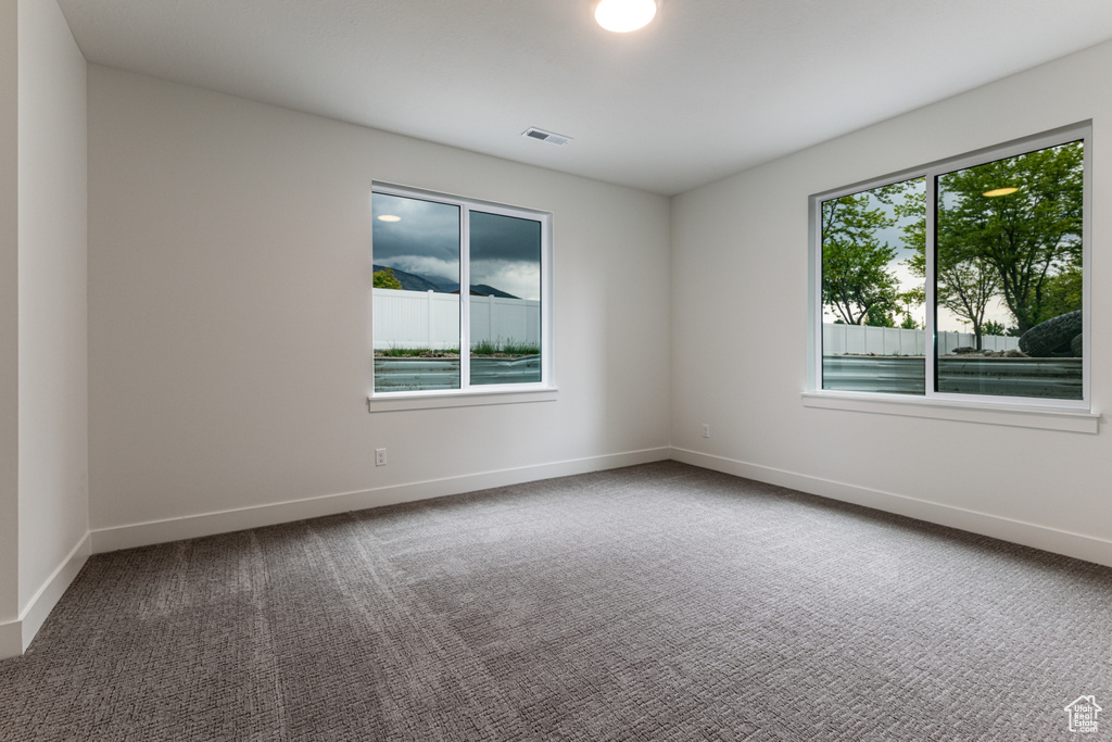 Carpeted spare room with baseboards and visible vents