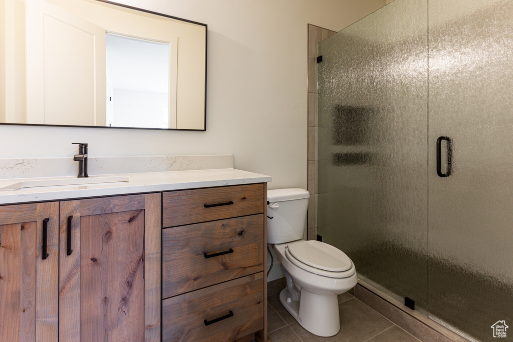 Full bathroom with a stall shower, vanity, toilet, and tile patterned floors