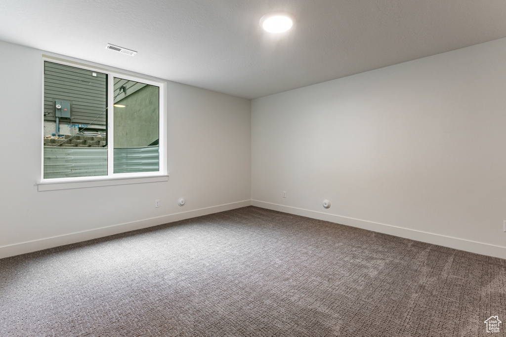 Carpeted empty room featuring visible vents and baseboards