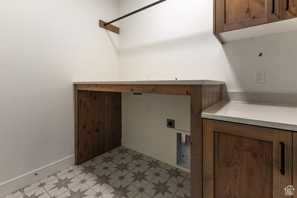 Clothes washing area featuring cabinet space, light floors, baseboards, and hookup for an electric dryer