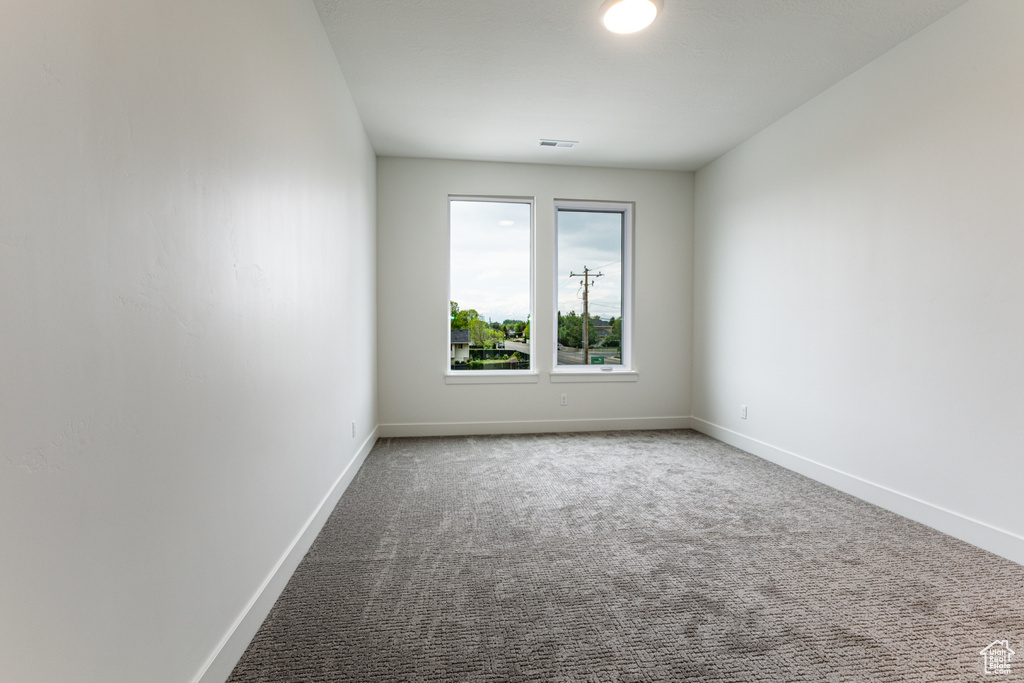 Unfurnished room with carpet flooring, baseboards, and visible vents