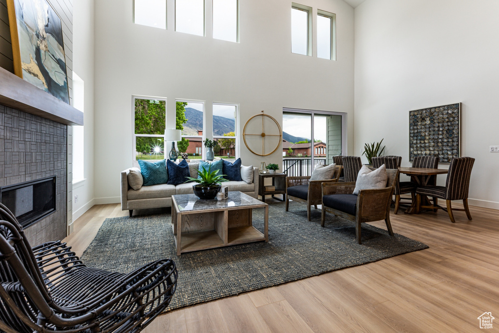 Living area with a fireplace, a high ceiling, baseboards, and wood finished floors