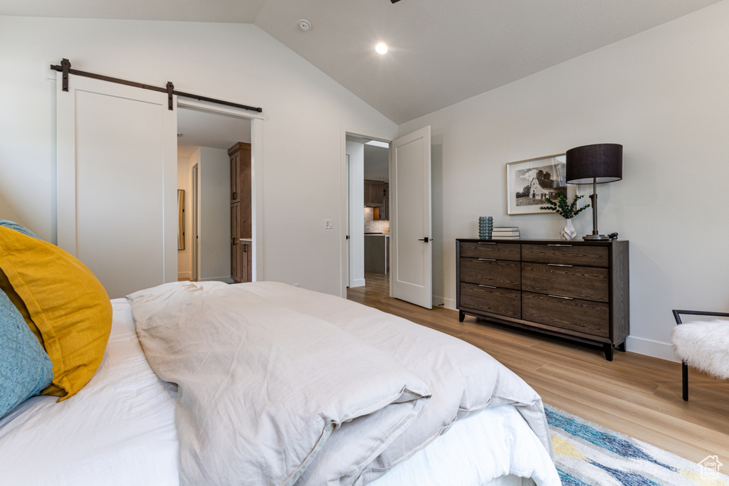 Bedroom with a barn door, baseboards, light wood-style floors, vaulted ceiling, and recessed lighting