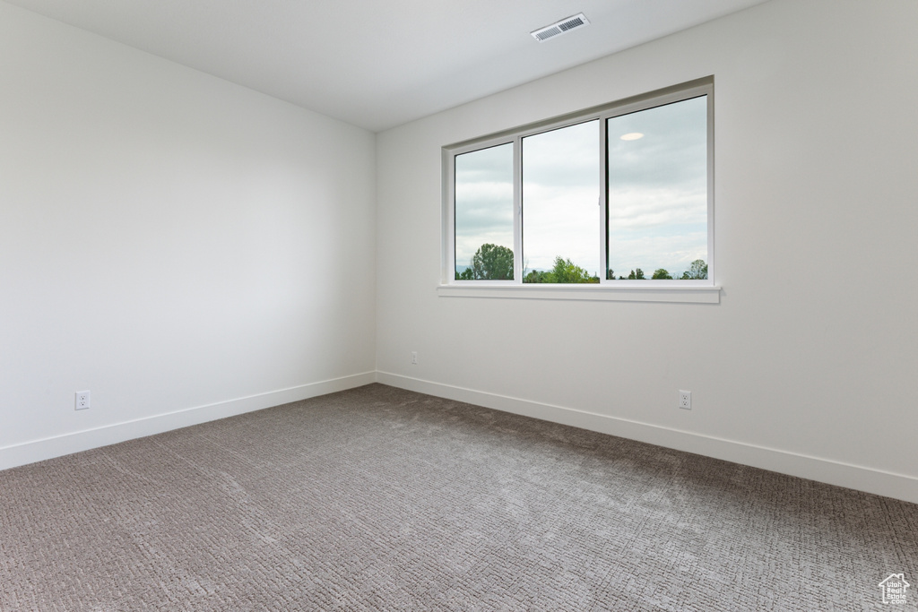Carpeted spare room with visible vents and baseboards