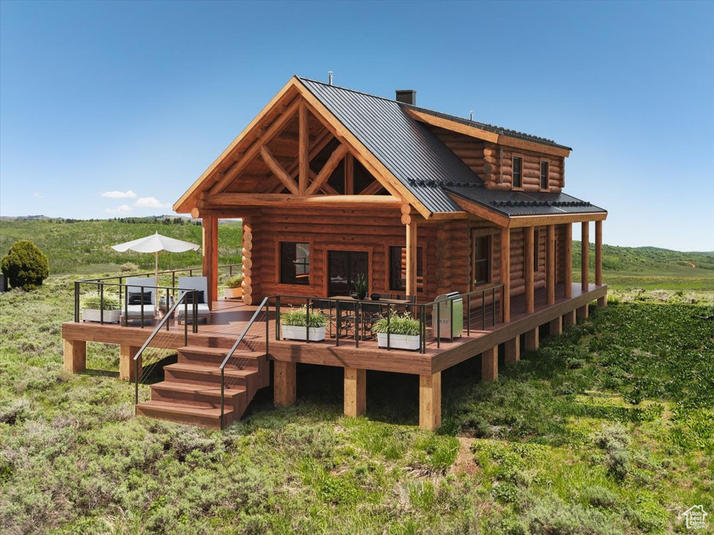 Rear view of house with log siding, a deck, and metal roof