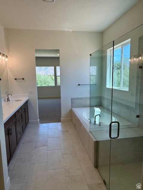 Full bath with double vanity, a garden tub, a stall shower, baseboards, and tile patterned floors