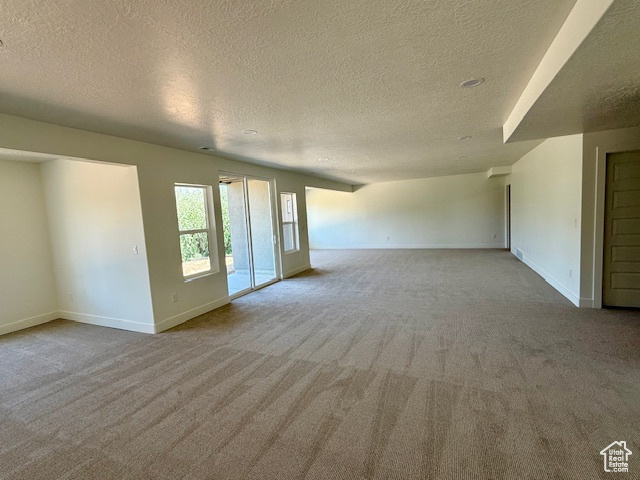 Empty room featuring carpet floors, a textured ceiling, and baseboards