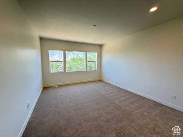 Carpeted empty room with recessed lighting and baseboards