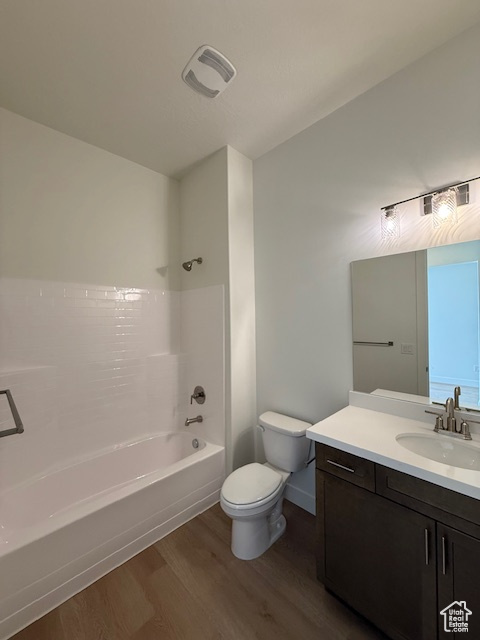 Full bathroom featuring wood finished floors, toilet,  shower combination, vanity, and baseboards