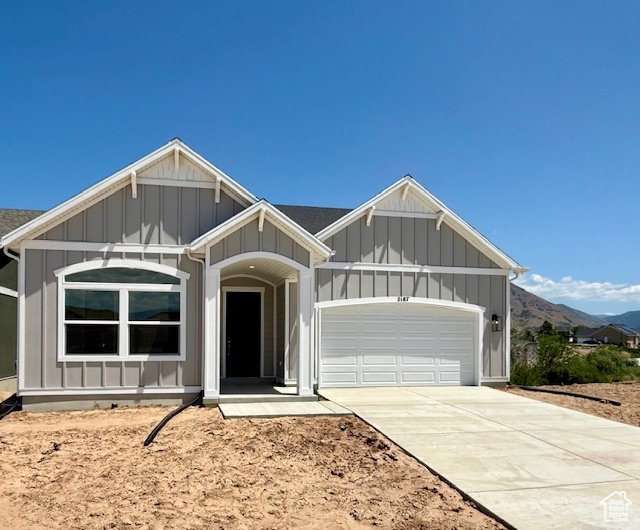 View of front of house with board and batten siding, an attached garage, driveway, and a mountain view