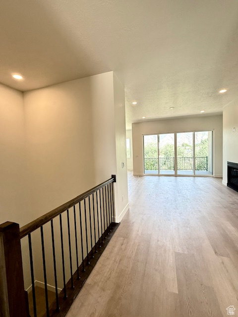 Hall with wood finished floors, an upstairs landing, recessed lighting, and baseboards