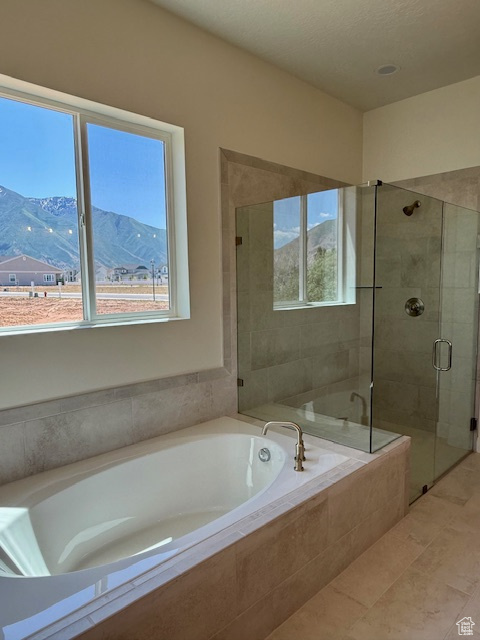 Bathroom featuring a shower stall, a garden tub, a mountain view, and tile patterned flooring