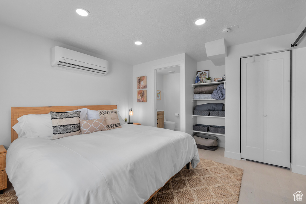 Bedroom with a wall mounted AC, recessed lighting, and a closet