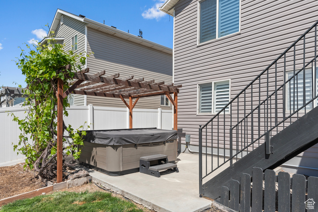 Fenced backyard with a hot tub, a patio, and a pergola