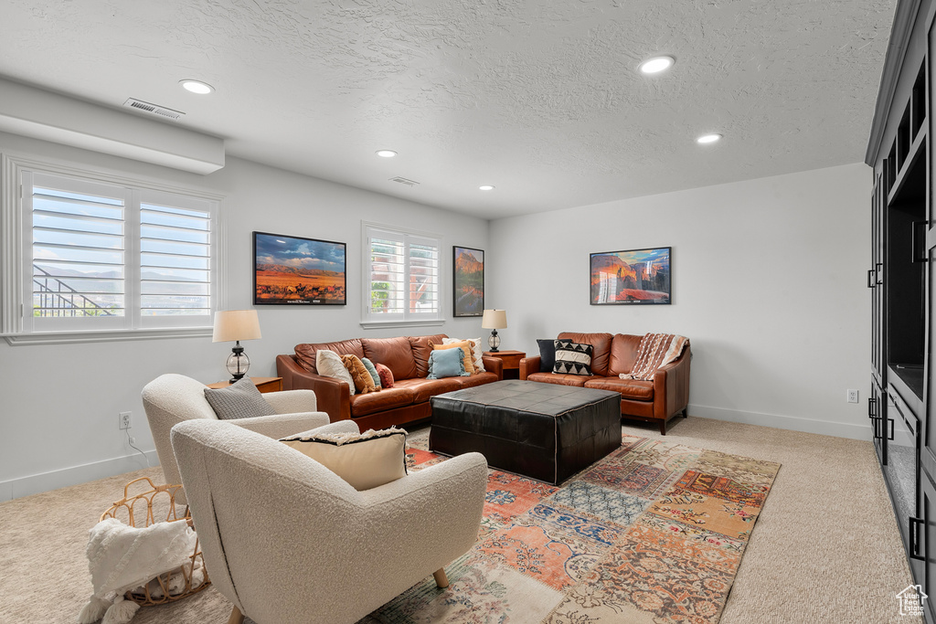 Living room featuring light colored carpet, recessed lighting, a textured ceiling, and baseboards