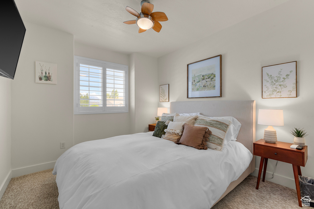 Bedroom with light carpet, baseboards, and a ceiling fan