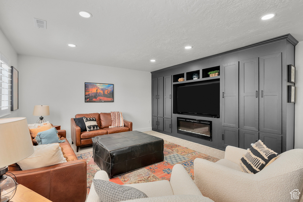 Living area with recessed lighting, baseboards, light carpet, and a textured ceiling