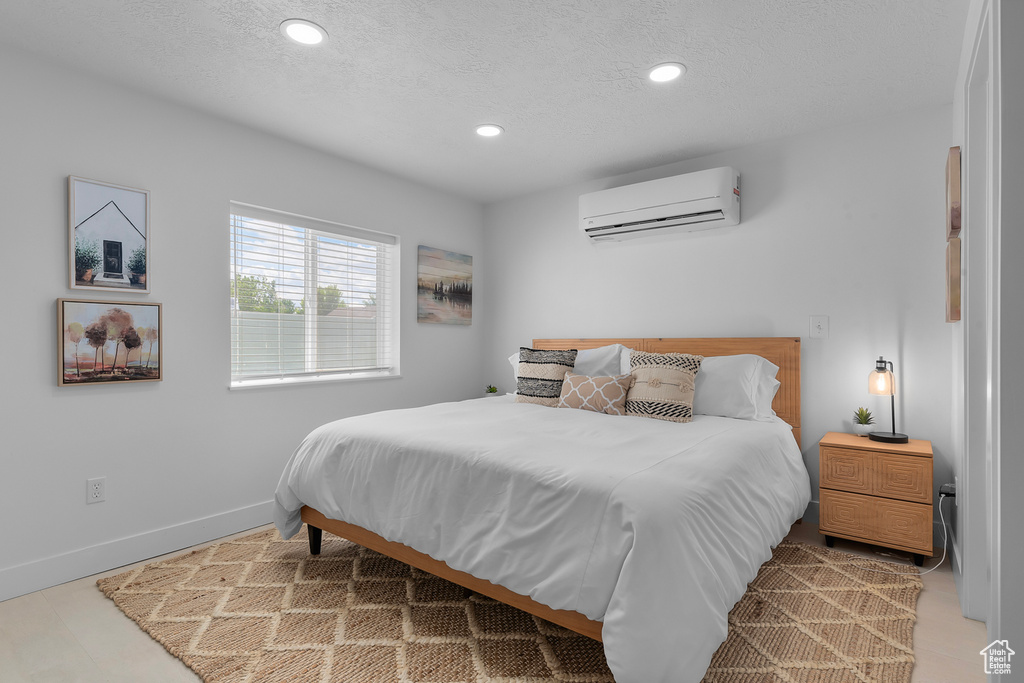 Bedroom with a wall mounted AC, recessed lighting, a textured ceiling, and baseboards