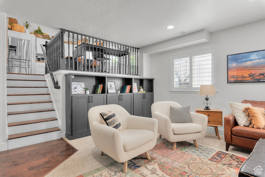 Living room with light colored carpet, stairway, recessed lighting, and a textured ceiling